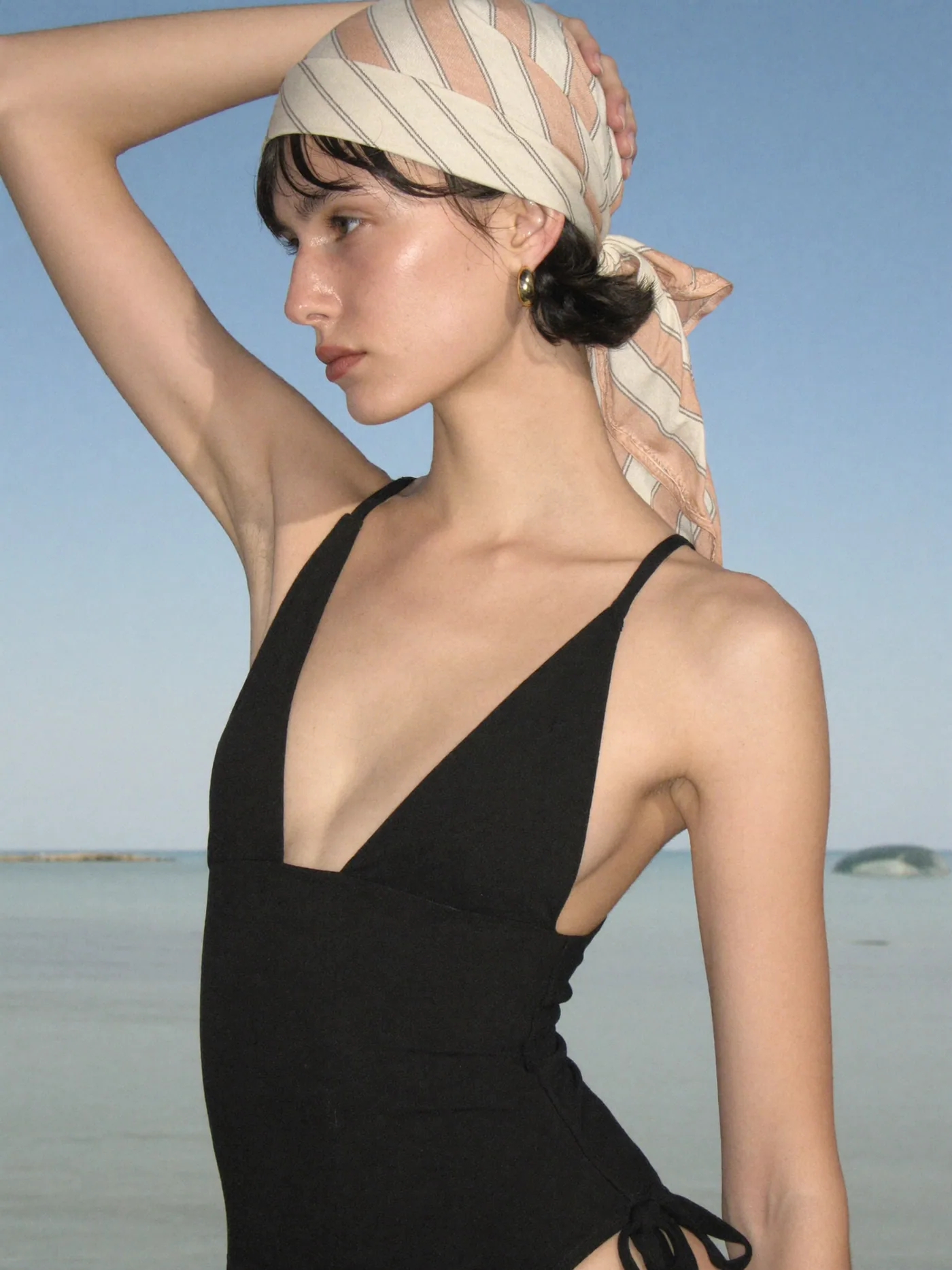 Perfil com lenço listrado à beira-mar